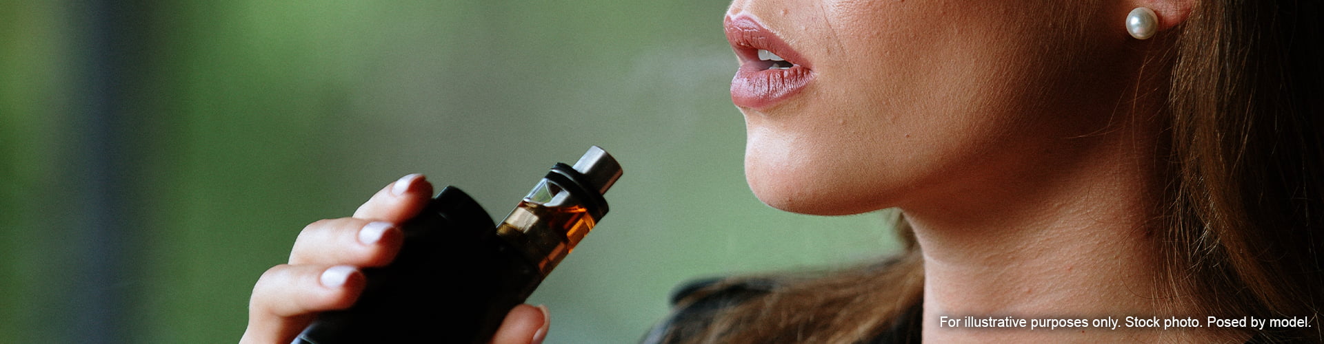 Woman holding vape with brown e-liquid